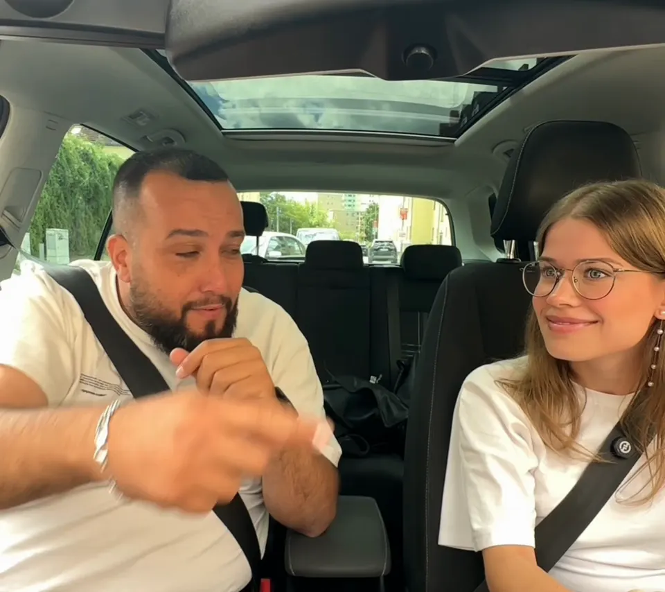 Tolga muss lachen, die Fahrschülerin grinst